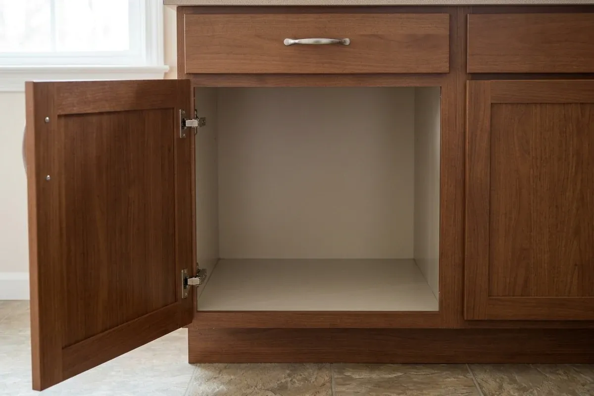 An open base cabinet with visible hinge intrusion and empty interior