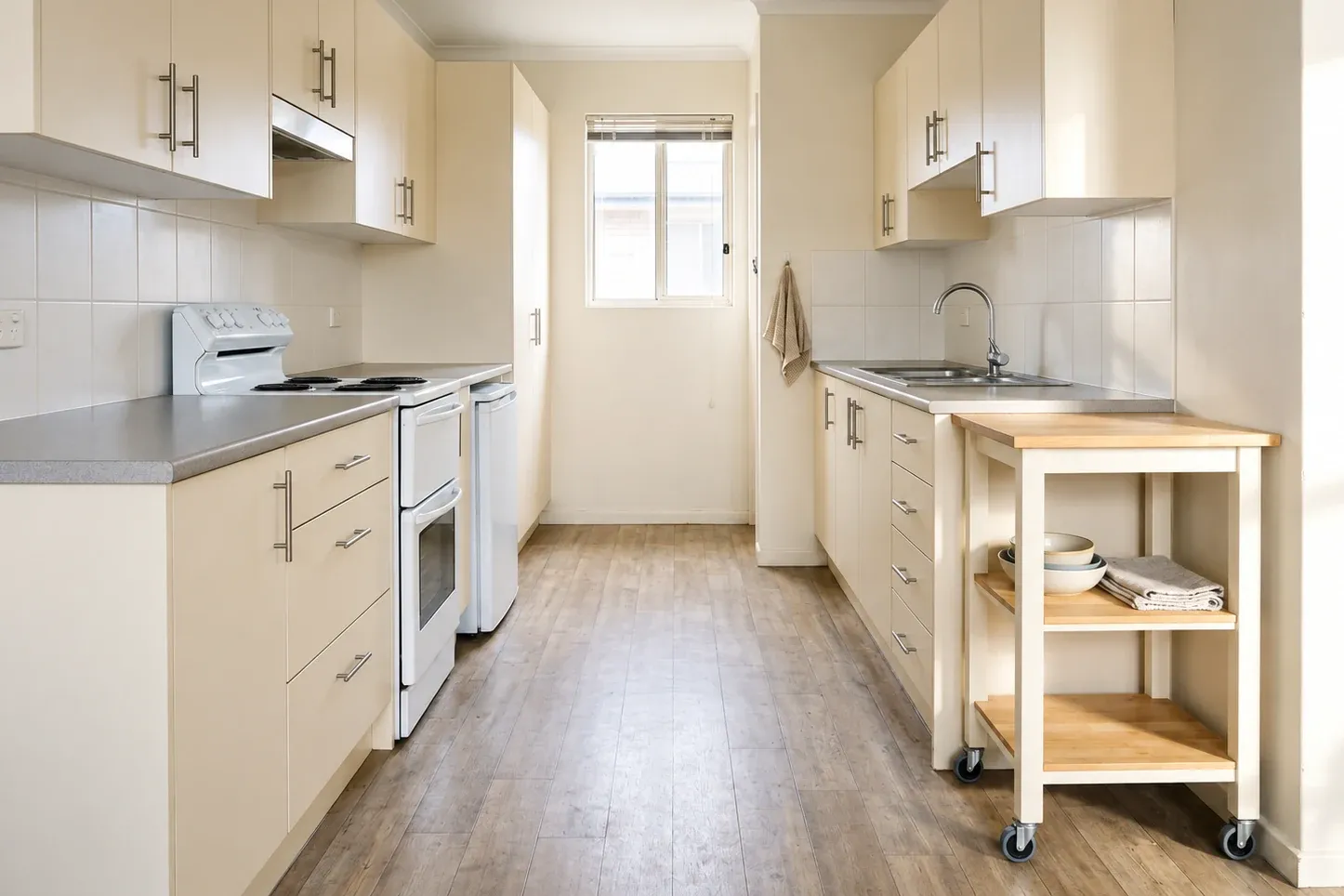 A small kitchen with existing cabinets and a freestanding storage cart beside the work area